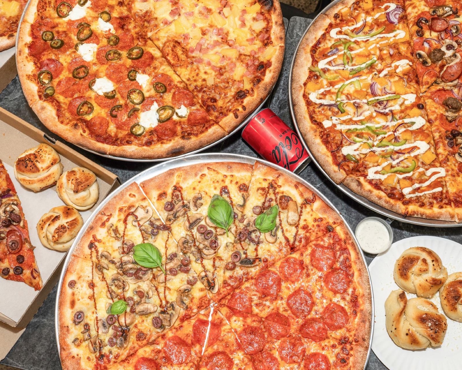 A spread of New York-style pizzas and garlic knots at Pizza Kai