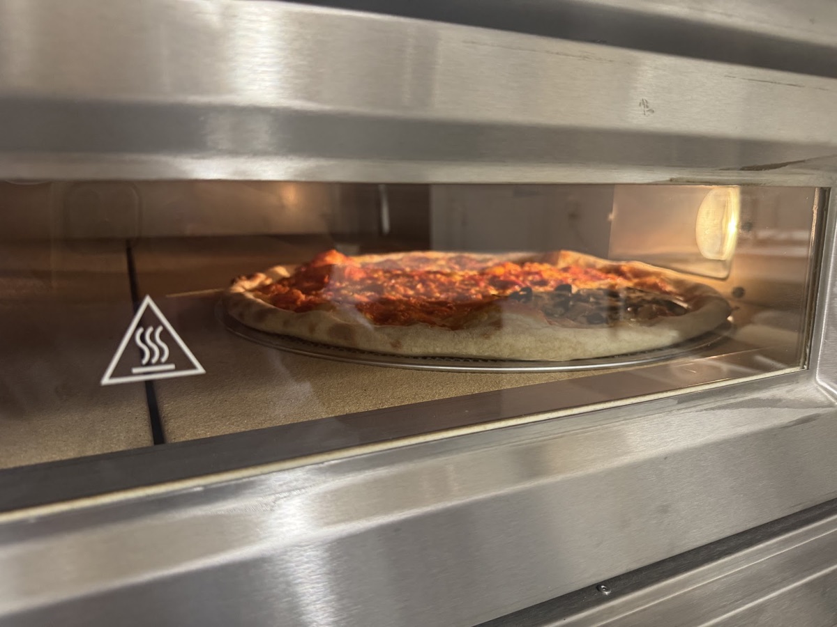 A pizza baking in the deck oven at Pizza Kai