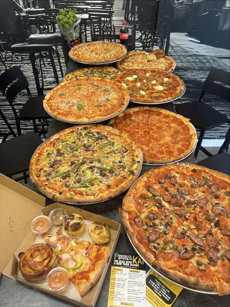 A table full of fresh Pizza Kai pizzas and pinwheels